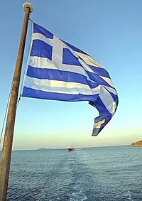 Griechische Nationalflagge im Wind auf einer Fähre mit Blick aufs Ägäische Meer