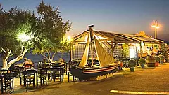 Beleuchtete Taverna Avra in Kalamaki auf Kreta bei Nacht mit dekorativem Fischerboot