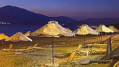 Strand von Kalamaki auf Kreta bei Nacht mit Liegestühlen und Sonnenschirmen vor beleuchteten Bergen
