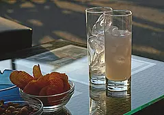 Kühle Getränke mit Eis und Chips auf einem Glastisch im Abendlicht auf Kreta